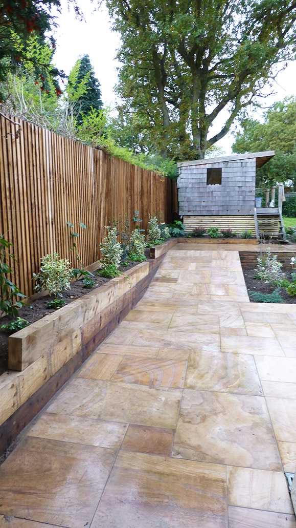 view of the side fencing and sloped patio leading up to the shed