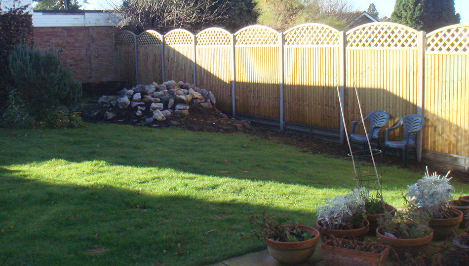 Sloped patio and steps leading up to a raised shed and gently curved lawn