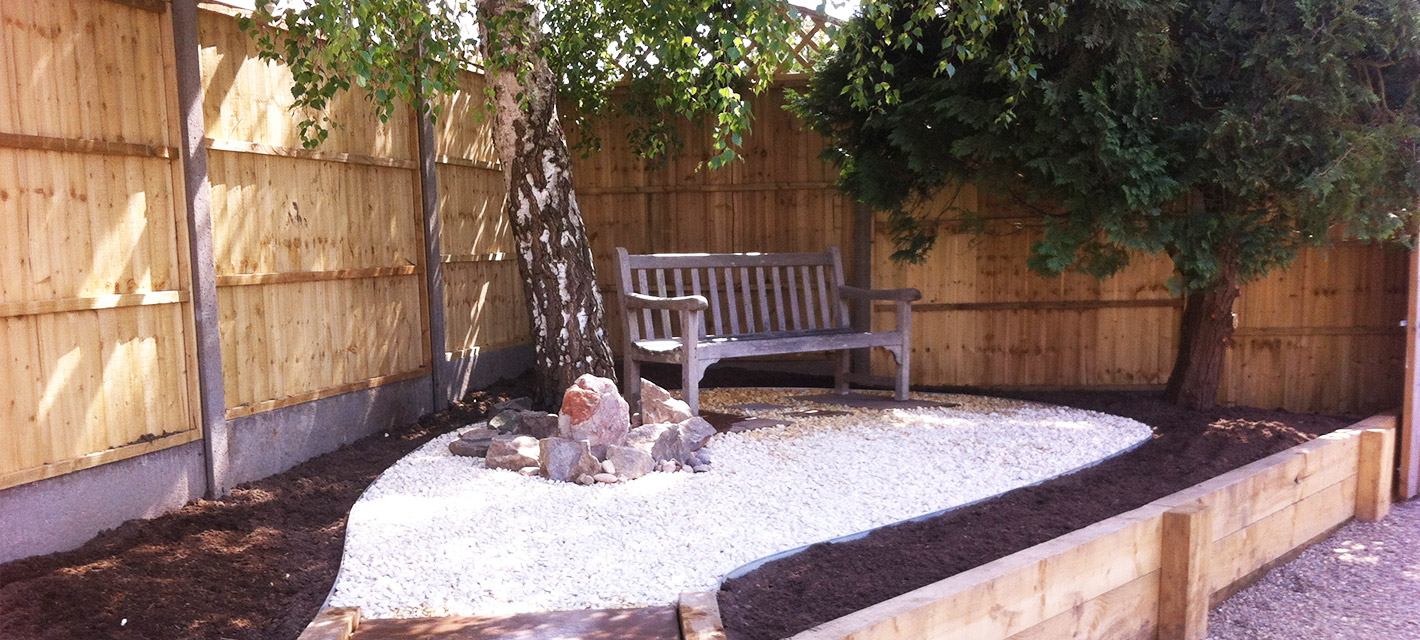 Sloped patio and steps leading up to a raised shed and gently curved lawn